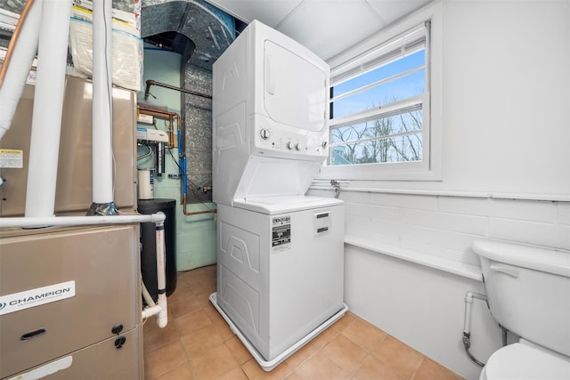 laundry room featuring heating unit, light tile patterned floors, and stacked washing maching and dryer