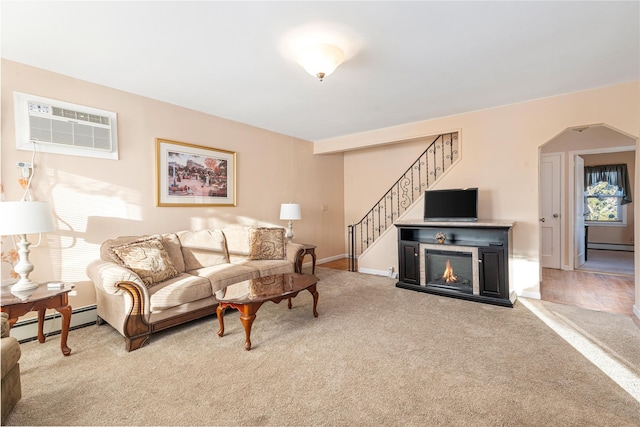 carpeted living room featuring a baseboard heating unit and an AC wall unit