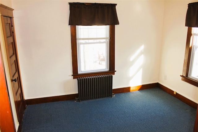 carpeted empty room featuring radiator heating unit