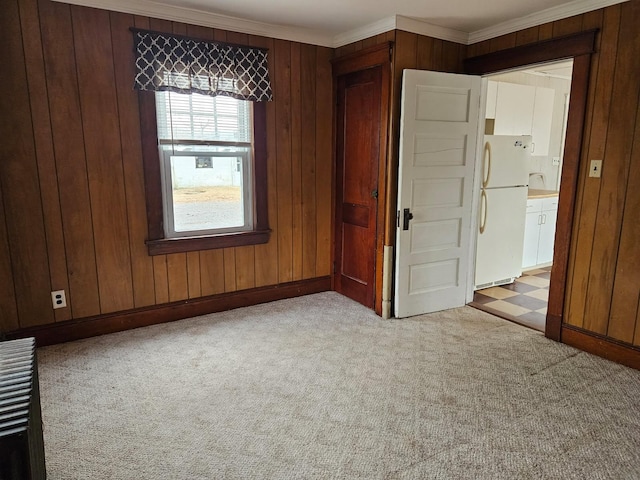 carpeted empty room featuring crown molding and wood walls