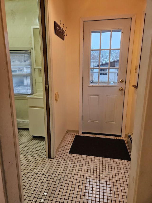 doorway to outside with light tile patterned flooring and a baseboard heating unit