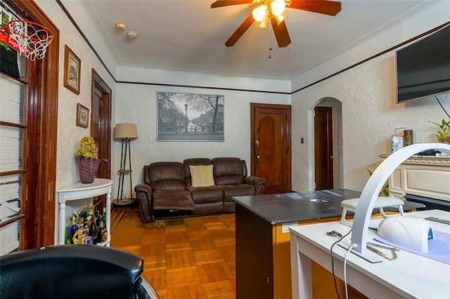 living room featuring dark parquet flooring, ornamental molding, and ceiling fan