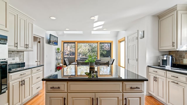 kitchen with decorative backsplash, light hardwood / wood-style floors, a kitchen island, and cream cabinetry