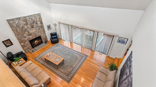 living room with high vaulted ceiling, a fireplace, and hardwood / wood-style floors