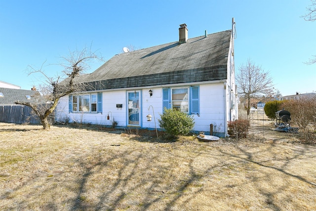 colonial inspired home with roof with shingles, a chimney, fence, and a front yard