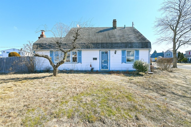 view of front of property featuring a chimney, fence, a front lawn, and roof with shingles