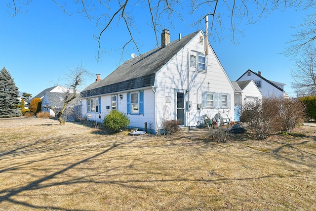 view of front of home with a front yard, roof with shingles, and a chimney