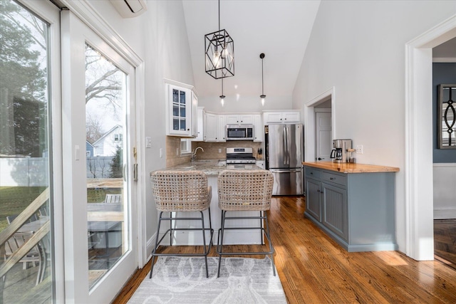 kitchen with butcher block countertops, appliances with stainless steel finishes, gray cabinetry, white cabinets, and kitchen peninsula