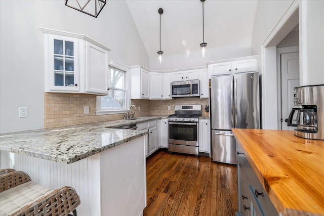 kitchen with white cabinetry, decorative light fixtures, kitchen peninsula, and appliances with stainless steel finishes