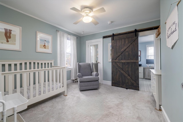 carpeted bedroom with ceiling fan, ornamental molding, a barn door, and a nursery area