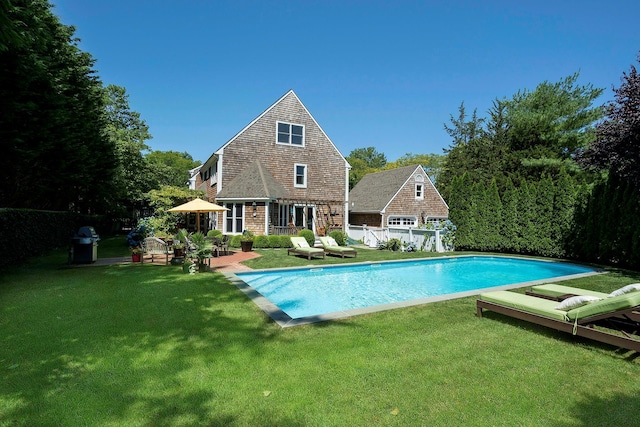 view of swimming pool with a grill, an outbuilding, and a lawn