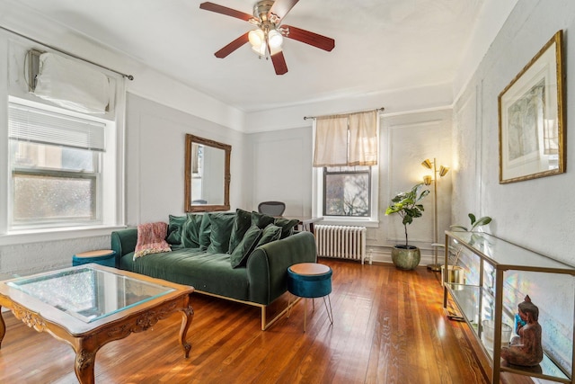 sitting room featuring radiator, hardwood / wood-style floors, and ceiling fan