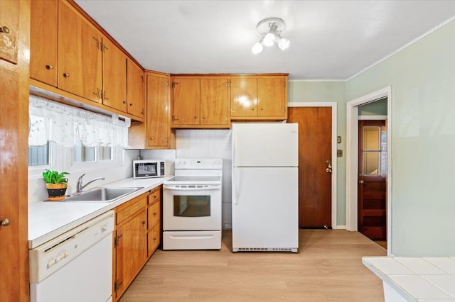 kitchen with crown molding, light wood-type flooring, sink, and white appliances