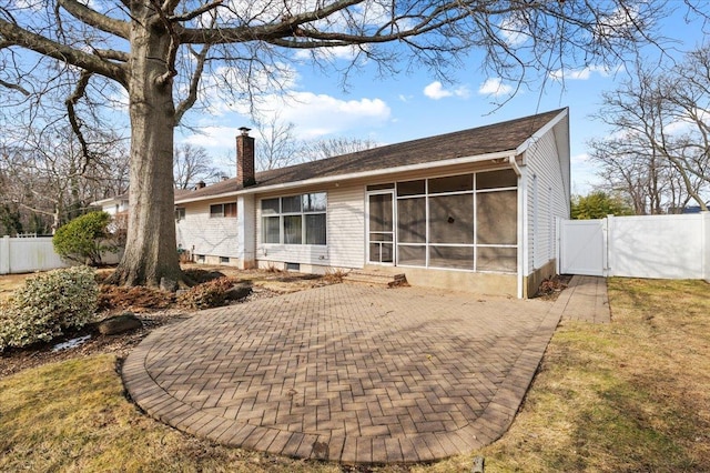 rear view of house with a sunroom, a yard, and a patio area