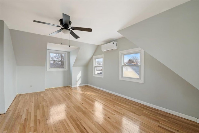 additional living space featuring ceiling fan, lofted ceiling, light hardwood / wood-style flooring, and an AC wall unit