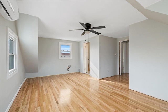 unfurnished room featuring ceiling fan, a wall mounted AC, and light hardwood / wood-style floors