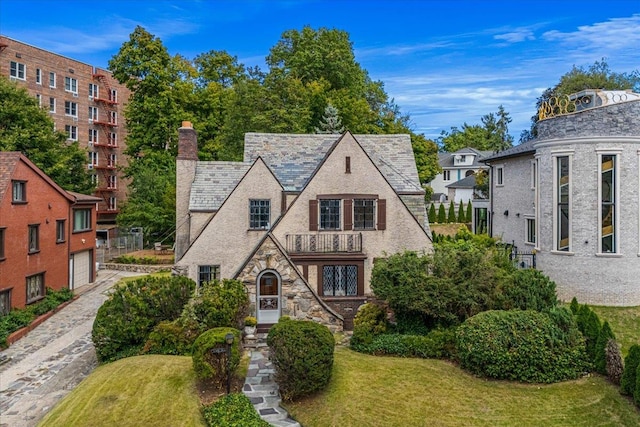 240-25 Alameda Ave, Douglaston, NY 11362 - tudor house with a front yard, stone siding, a balcony, a chimney, and a garage