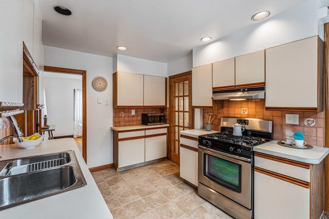 240-25 Alameda Ave, Douglaston, NY 11362 - kitchen featuring a sink, light countertops, under cabinet range hood, stainless steel appliances, and decorative backsplash