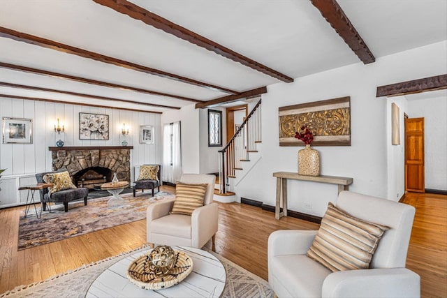 240-25 Alameda Ave, Douglaston, NY 11362 - living room with a stone fireplace, stairway, wood finished floors, baseboards, and beam ceiling