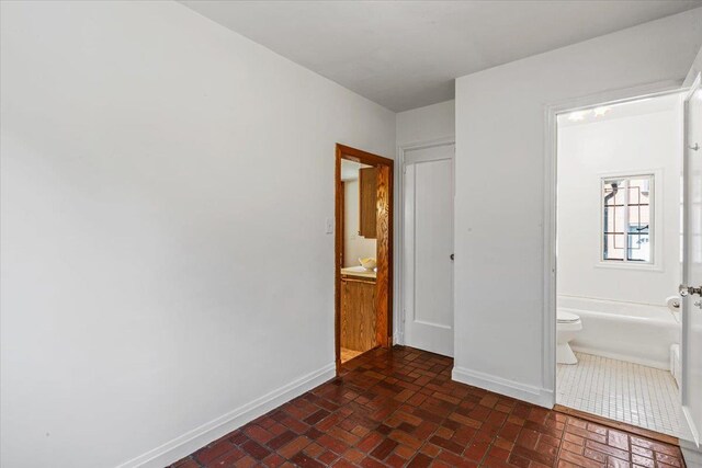 240-25 Alameda Ave, Douglaston, NY 11362 - unfurnished bedroom featuring ensuite bathroom, baseboards, and brick floor