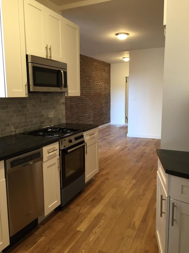 kitchen featuring tasteful backsplash, wood-type flooring, stainless steel appliances, and white cabinets