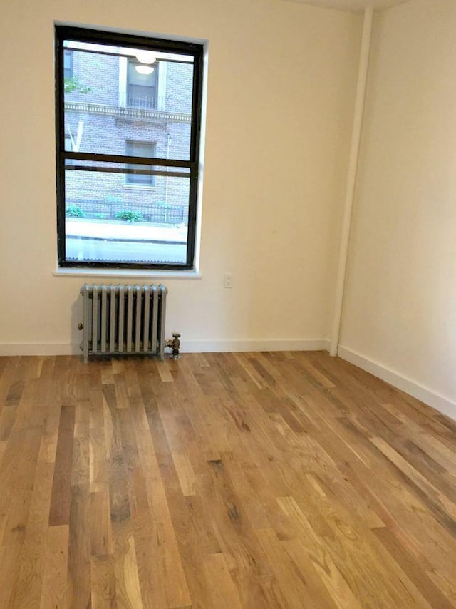 unfurnished room with radiator heating unit and hardwood / wood-style floors