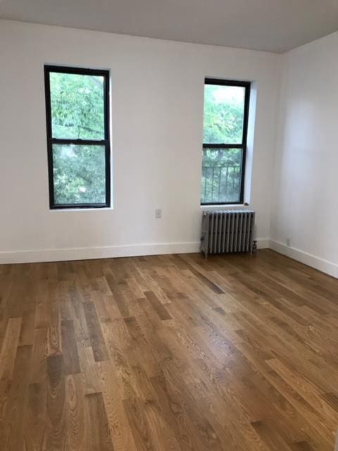 spare room with hardwood / wood-style flooring and radiator