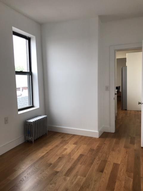 unfurnished room featuring dark wood-type flooring and radiator heating unit