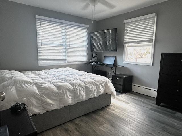 bedroom with hardwood / wood-style flooring, ceiling fan, and baseboard heating