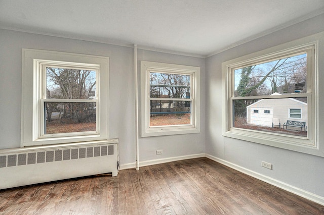 spare room with crown molding, radiator heating unit, and wood-type flooring