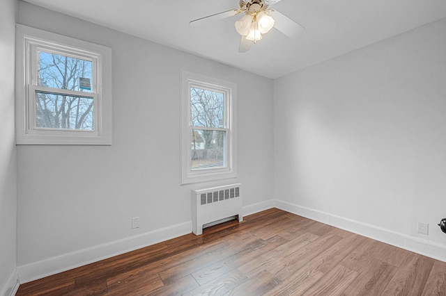 empty room with ceiling fan, radiator heating unit, and wood-type flooring