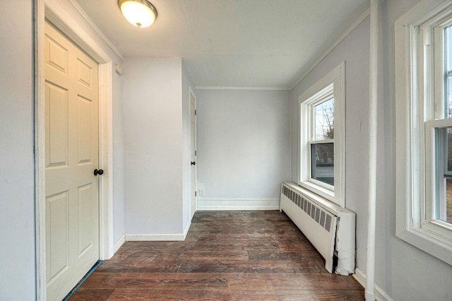 corridor featuring radiator, dark wood-type flooring, and ornamental molding