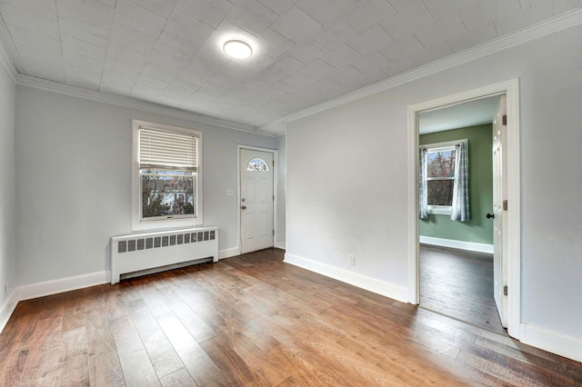 foyer entrance with ornamental molding, radiator heating unit, and hardwood / wood-style floors