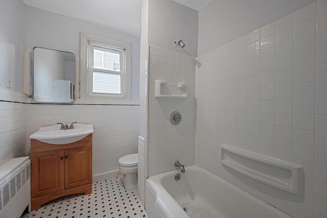 full bathroom featuring tile walls, radiator heating unit, vanity, toilet, and tiled shower / bath