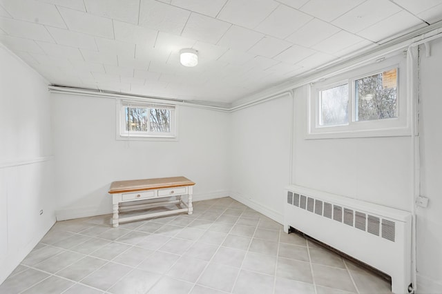 basement featuring light tile patterned floors, a wealth of natural light, and radiator heating unit