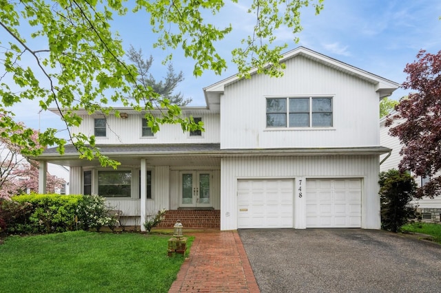 traditional-style house featuring french doors, asphalt driveway, a garage, and a front lawn