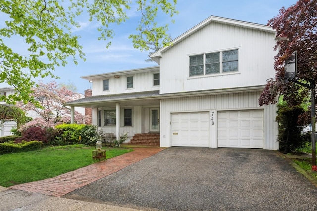 traditional-style house with asphalt driveway, a front lawn, and an attached garage