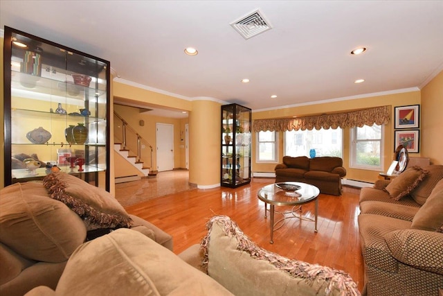 living area with crown molding, a baseboard heating unit, a baseboard radiator, baseboards, and stairs