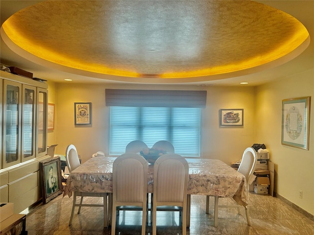 dining space featuring a tray ceiling, baseboards, and recessed lighting