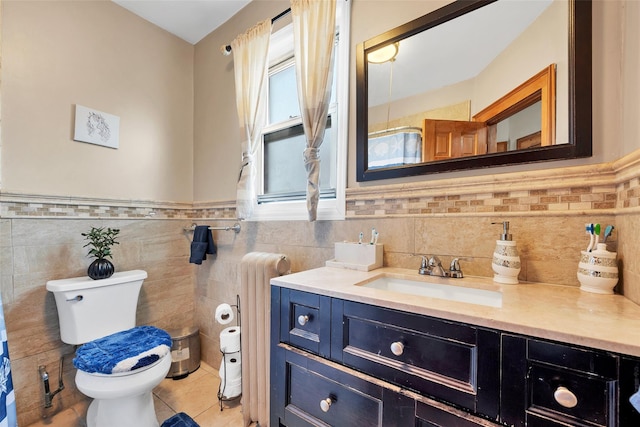 bathroom with tile patterned floors, toilet, tile walls, radiator heating unit, and vanity