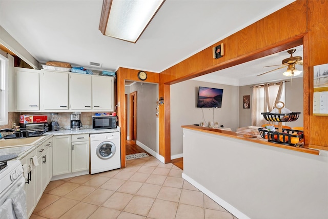 kitchen featuring sink, tasteful backsplash, white cabinets, washer / dryer, and white gas stove