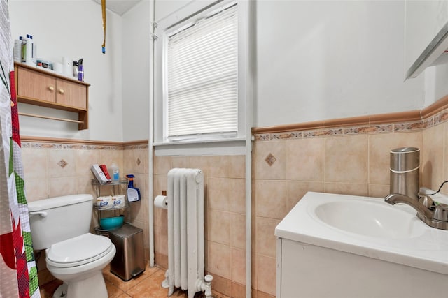 bathroom with tile patterned floors, toilet, tile walls, radiator heating unit, and vanity