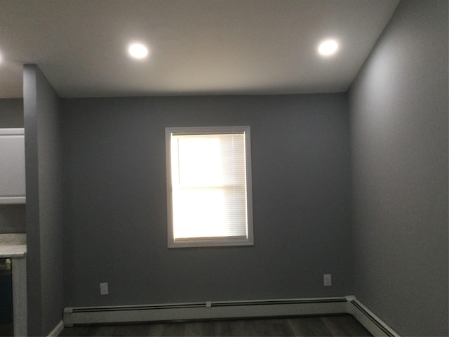 spare room with dark wood-type flooring and baseboard heating