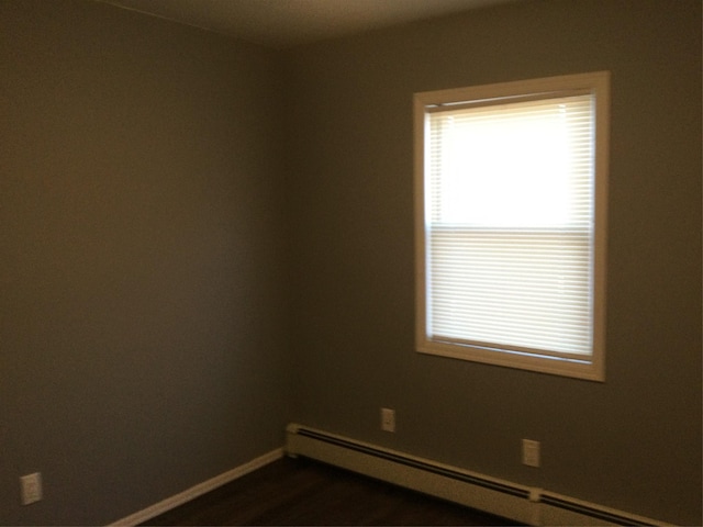 spare room with a baseboard radiator, dark hardwood / wood-style floors, and a healthy amount of sunlight