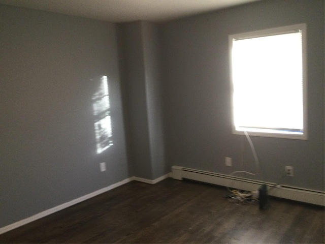 spare room featuring a baseboard radiator and dark hardwood / wood-style floors