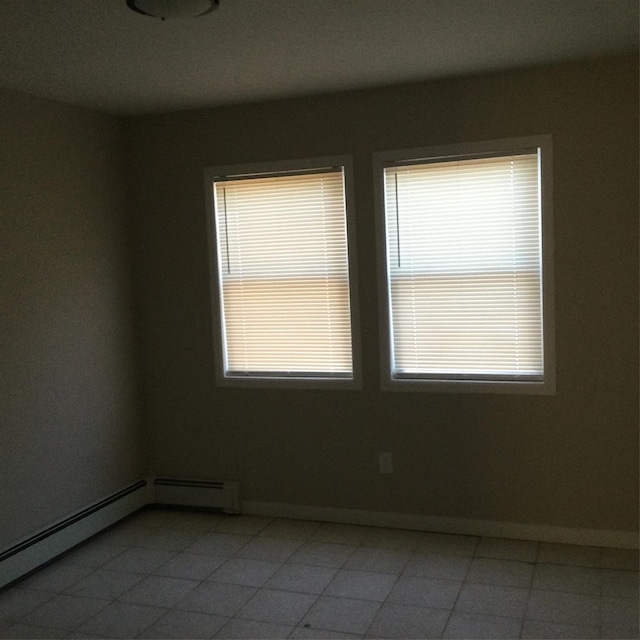 tiled spare room featuring a baseboard heating unit