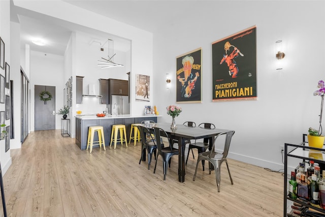 dining room featuring a towering ceiling and light wood-type flooring