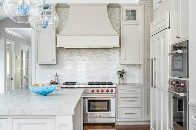 kitchen with backsplash, high end appliances, light stone counters, ornamental molding, and custom range hood