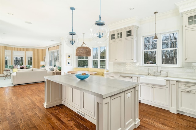 kitchen featuring tasteful backsplash, sink, a center island, crown molding, and dark wood-type flooring