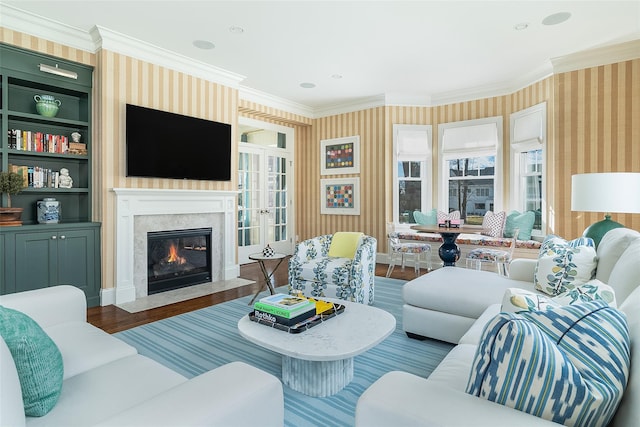 living room featuring hardwood / wood-style floors, crown molding, a premium fireplace, and built in shelves